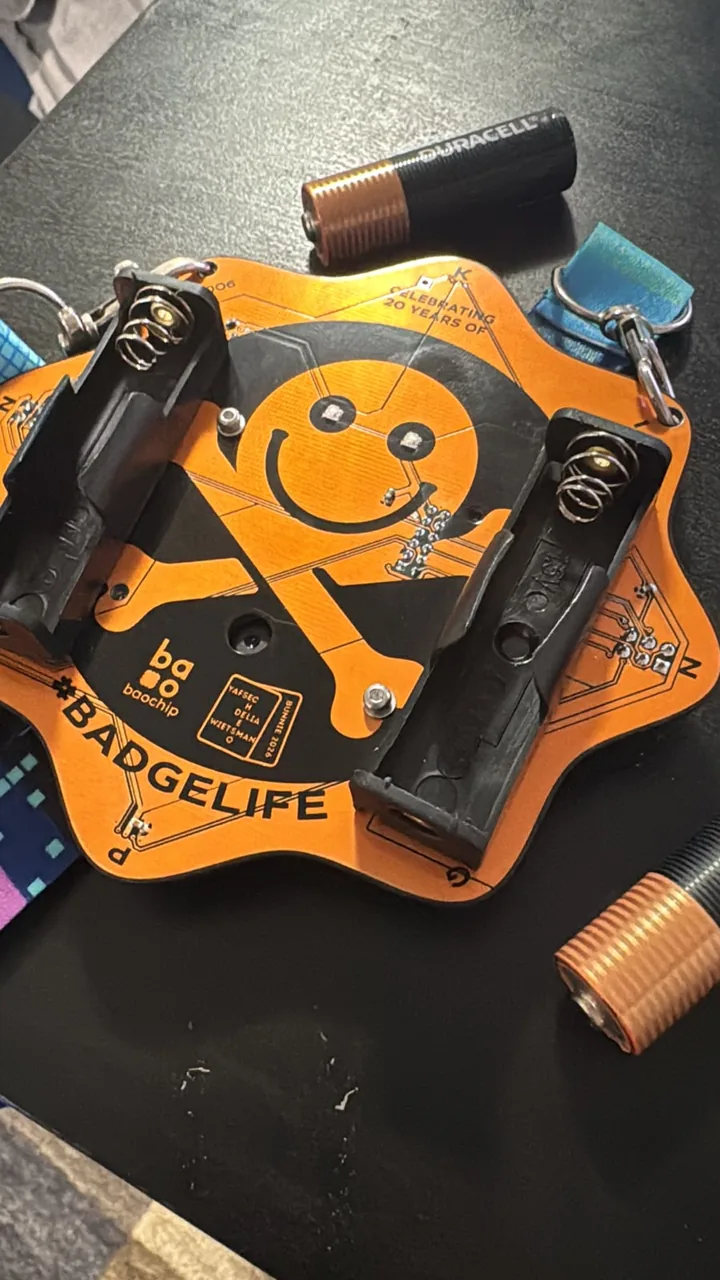 The DEF CON 34 badge with its batteries removed and the holders open